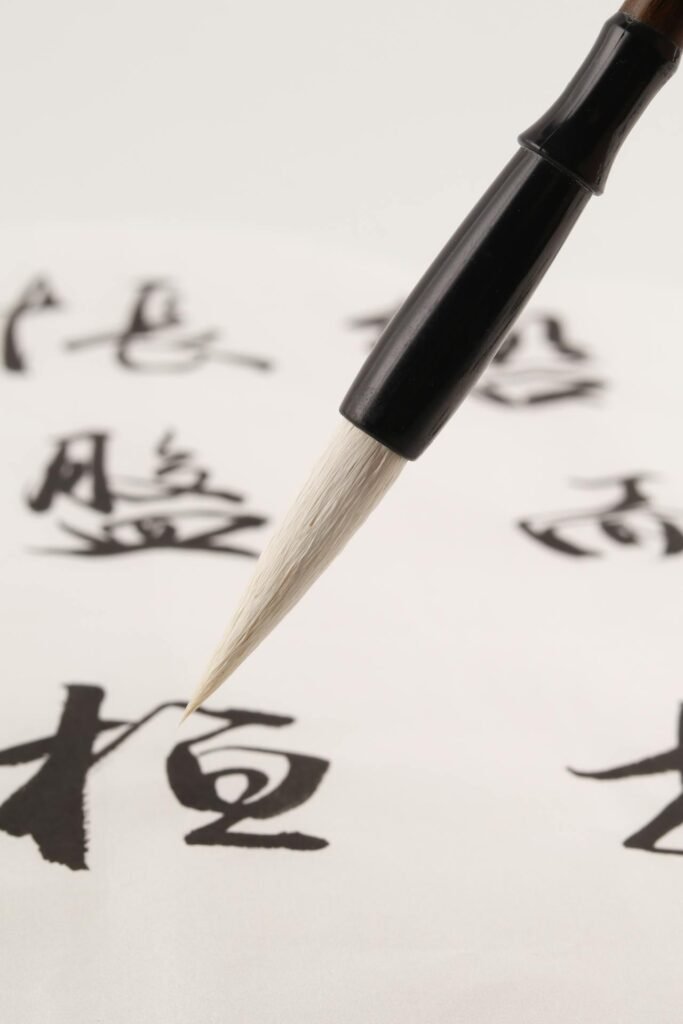 Pincel escribiendo caracteres japoneses durante una lección de  caligrafía, ideal para aprender japonés online en 2025.